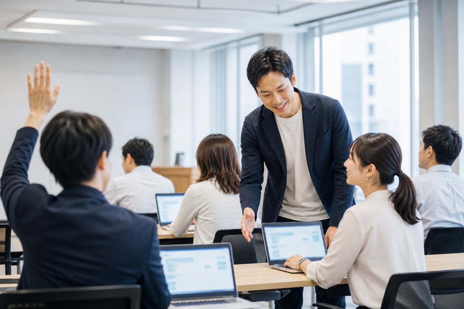 研修室で講師が受講者のノートPCをのぞき込みながら教えている様子